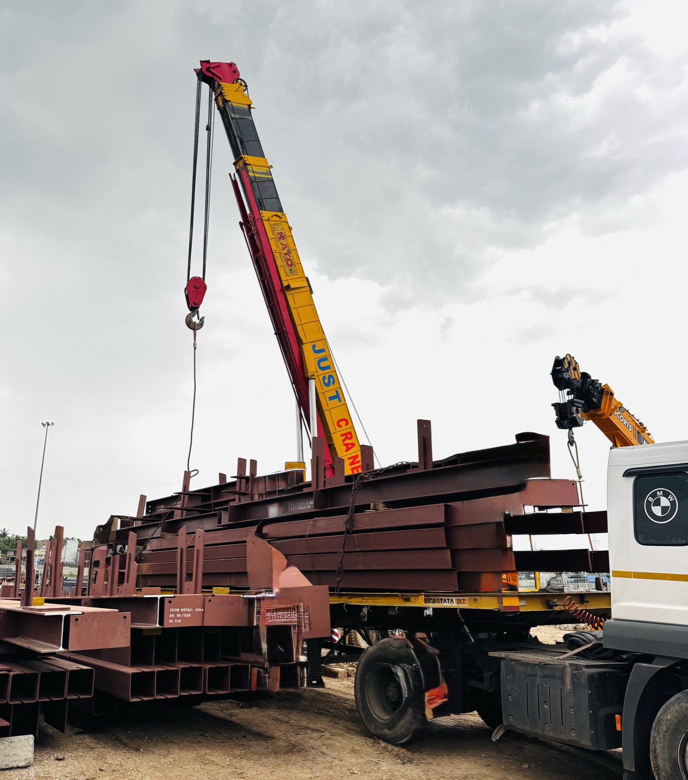 Mobile crane loading structural steel beams onto a trailer